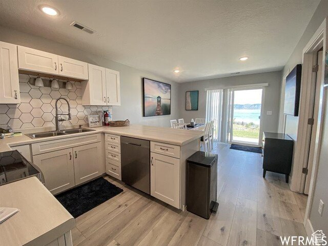 942 N Newberg Dr Unit 2, Garden City, UT 84028 - kitchen featuring dishwasher, visible vents, a sink, a peninsula, and white cabinetry
