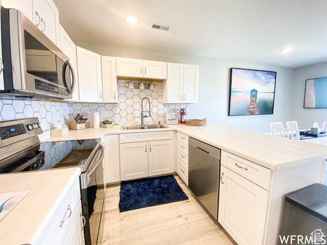 942 N Newberg Dr Unit 2, Garden City, UT 84028 - kitchen with backsplash, visible vents, a sink, a peninsula, and appliances with stainless steel finishes