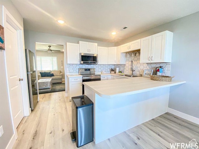942 N Newberg Dr Unit 2, Garden City, UT 84028 - kitchen featuring light countertops, a sink, a peninsula, appliances with stainless steel finishes, and white cabinetry