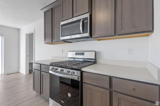 1131 W High Plains Dr Unit 601, Grantsville, UT 84029 - kitchen with stainless steel appliances, light wood finished floors, light countertops, dark brown cabinets, and a textured ceiling