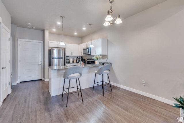 548 E 300 N, Vineyard, UT 84059 - kitchen featuring white cabinets, stainless steel appliances, baseboards, wood finished floors, and a peninsula
