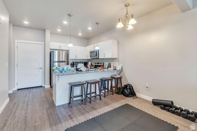 548 E 300 N, Vineyard, UT 84059 - kitchen featuring light wood-style floors, visible vents, a peninsula, white cabinets, and appliances with stainless steel finishes
