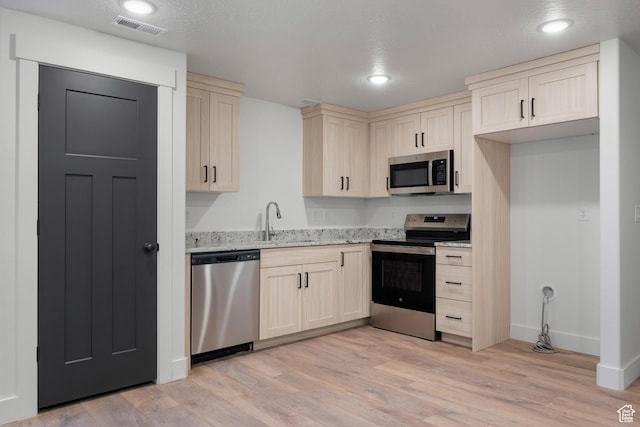 292 500 N, Santaquin, UT 84655 - kitchen featuring visible vents, a sink, light wood-type flooring, appliances with stainless steel finishes, and light stone counters