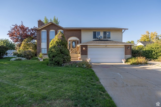 bi-level home featuring a chimney, a front lawn, driveway, and brick siding