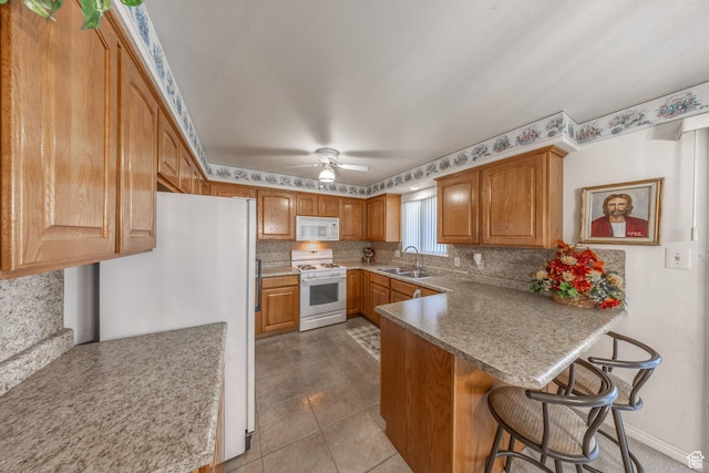 27 E Monticello Dr S, Kaysville, UT 84037 - kitchen featuring a sink, decorative backsplash, white appliances, a kitchen bar, and a peninsula