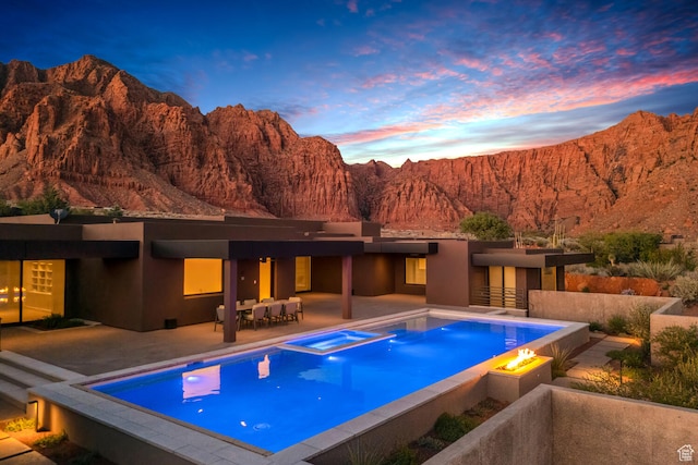 973 W Sipala Trl, Ivins, UT 84738 - pool at dusk featuring an in ground hot tub, a patio, and a mountain view