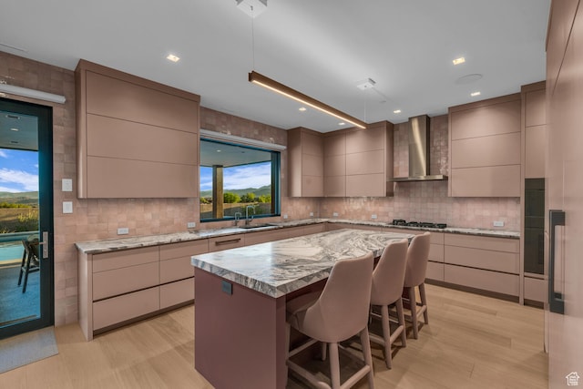 973 W Sipala Trl, Ivins, UT 84738 - kitchen featuring sink, a kitchen island, light hardwood / wood-style flooring, wall chimney exhaust hood, and a kitchen bar