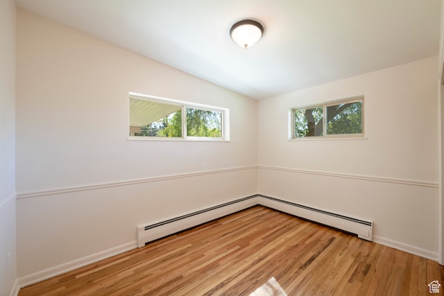 empty room featuring lofted ceiling, light hardwood / wood-style floors, and baseboard heating