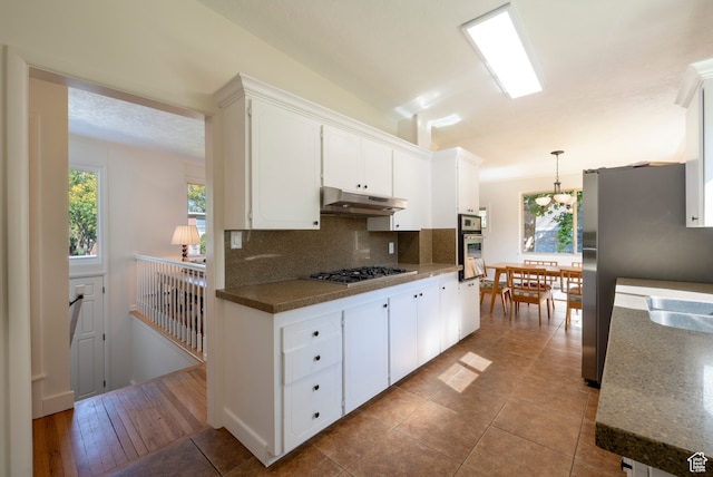 kitchen with pendant lighting, light hardwood / wood-style flooring, backsplash, white cabinetry, and appliances with stainless steel finishes