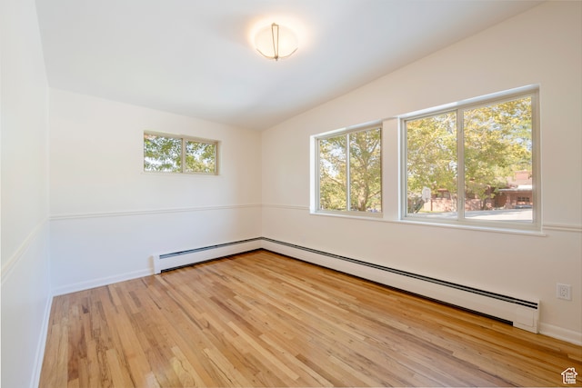 spare room featuring baseboard heating, plenty of natural light, and light hardwood / wood-style flooring
