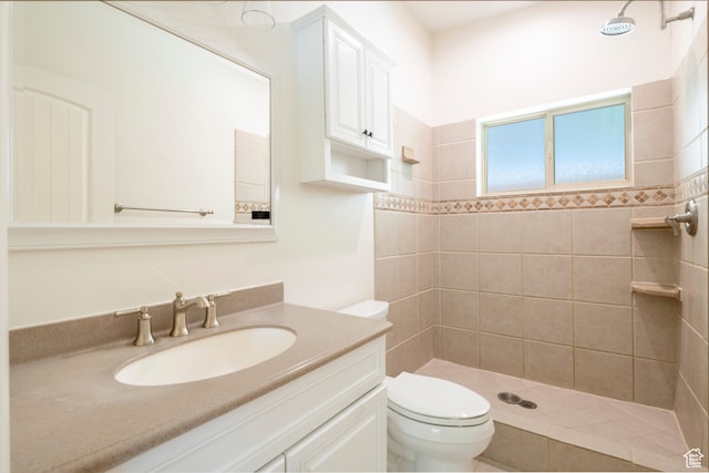 bathroom featuring a tile shower, vanity, and toilet