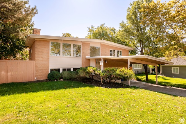 raised ranch featuring a front lawn and a carport