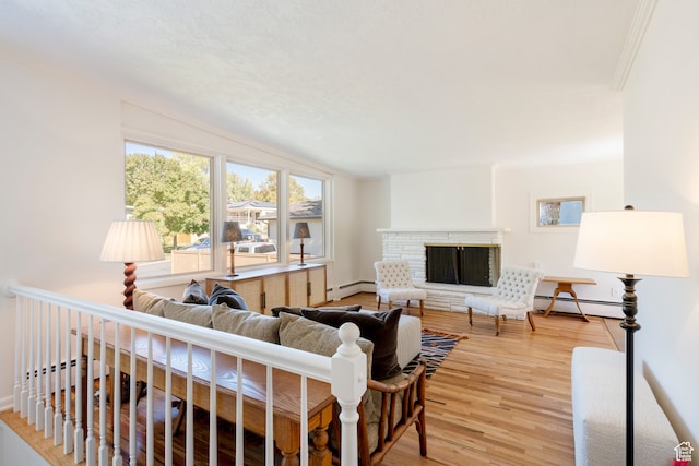 living room with a fireplace, baseboard heating, light hardwood / wood-style flooring, and vaulted ceiling