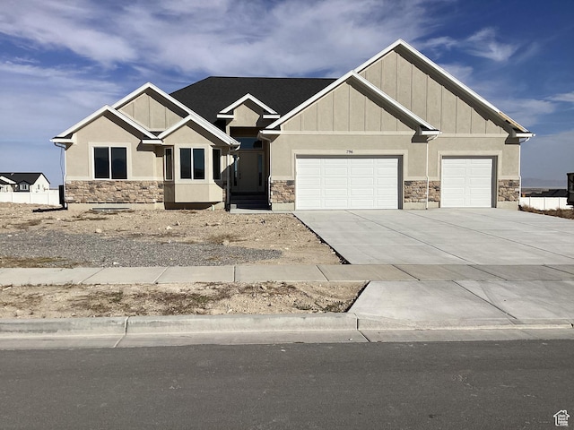 view of front of property with board and batten siding, concrete driveway, a garage, and stone siding