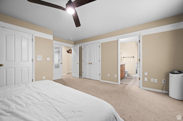 carpeted bedroom with ensuite bathroom, baseboards, ceiling fan, and visible vents