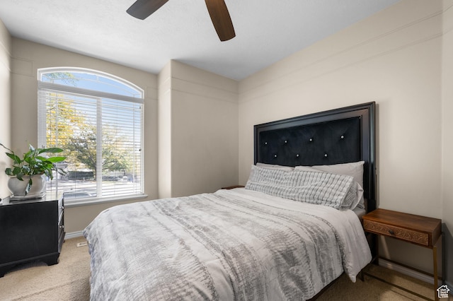 bedroom with baseboards, multiple windows, light carpet, and a ceiling fan