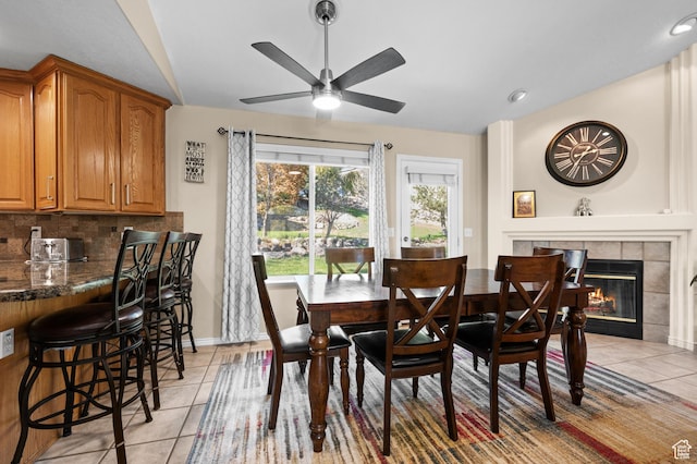 dining room with light tile patterned floors, ceiling fan, a tile fireplace, and lofted ceiling