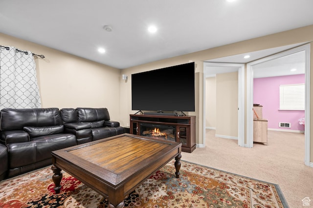 carpeted living room featuring visible vents, recessed lighting, baseboards, and a glass covered fireplace