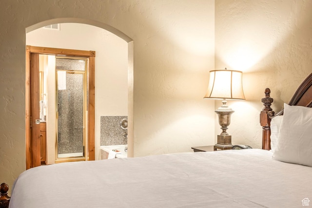 bedroom with a textured wall, arched walkways, and visible vents
