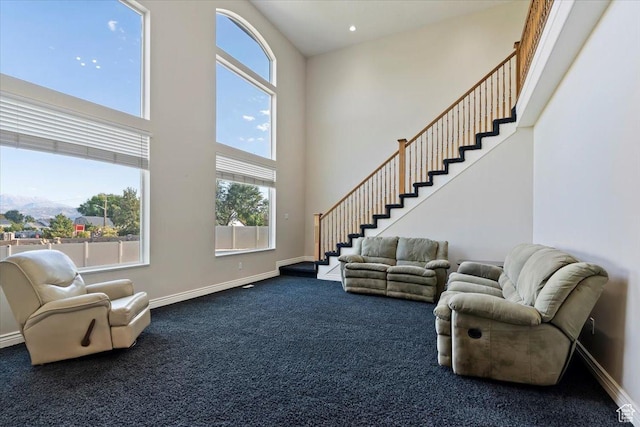 living room featuring baseboards, a healthy amount of sunlight, a high ceiling, and carpet flooring