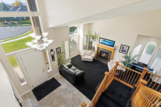 entrance foyer with visible vents, a high end fireplace, baseboards, a towering ceiling, and a notable chandelier