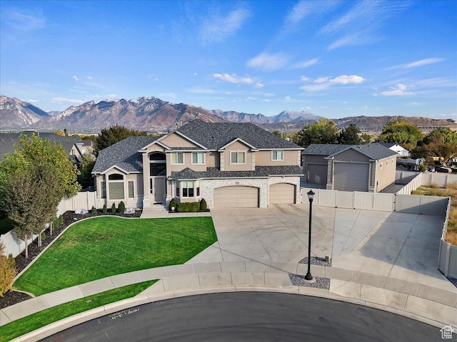 traditional-style home with a mountain view, fence, a front yard, and concrete driveway