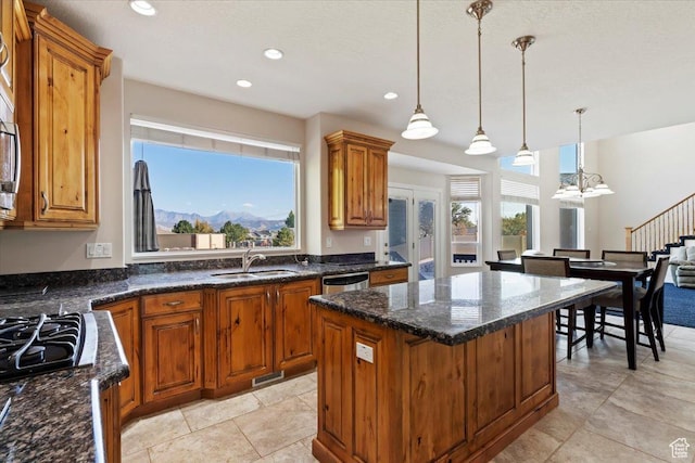 kitchen featuring a sink, brown cabinets, light tile patterned floors, a center island, and pendant lighting