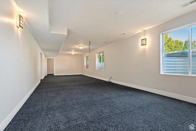 unfurnished room with visible vents, dark colored carpet, and baseboards