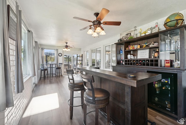 bar featuring a bar, wood finished floors, a ceiling fan, and wine cooler