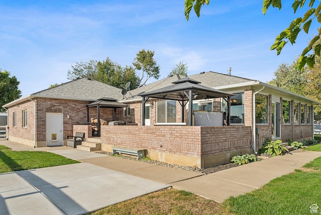 view of front of house with roof with shingles, a gazebo, a patio area, and brick siding