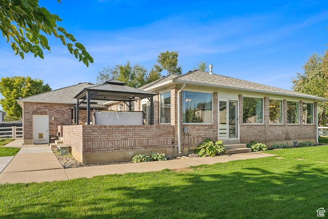 view of front of property featuring a front yard, a shingled roof, brick siding, a gazebo, and entry steps