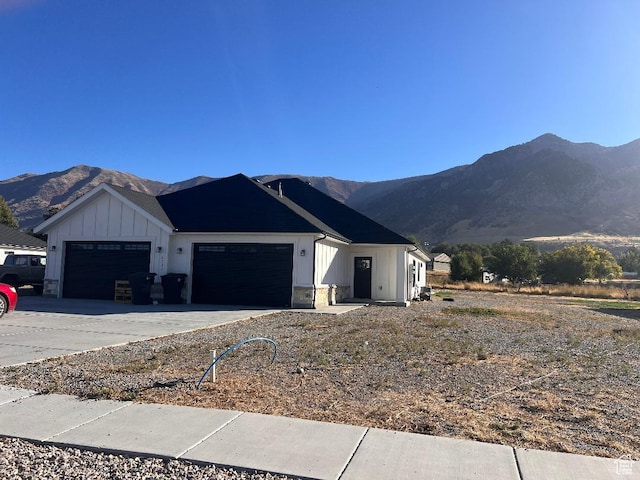 6916 N 2750 W, Honeyville, UT 84314 - view of front facade featuring concrete driveway, an attached garage, a mountain view, and board and batten siding