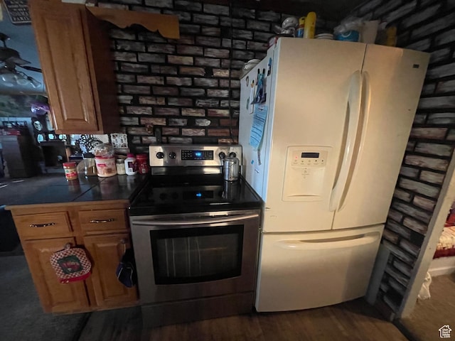 kitchen with brown cabinetry, stainless steel electric stove, dark wood-style flooring, and white fridge with ice dispenser