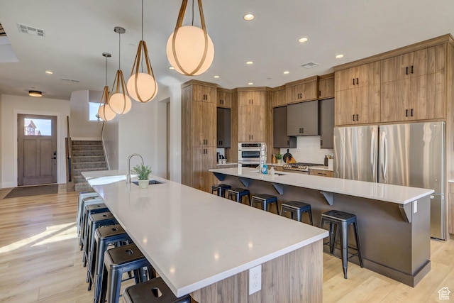 4971 S Cattail Way, Washington, UT 84780 - kitchen featuring visible vents, a large island, a breakfast bar, light wood-style floors, and stainless steel appliances