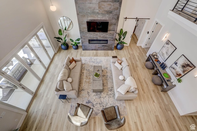 4971 S Cattail Way, Washington, UT 84780 - living room featuring a towering ceiling, a barn door, wood finished floors, a tile fireplace, and baseboards