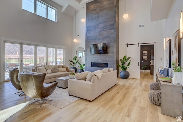 4971 S Cattail Way, Washington, UT 84780 - living room with a tiled fireplace, a towering ceiling, baseboards, and light wood-style flooring