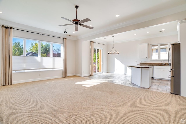 unfurnished living room with baseboards, recessed lighting, light colored carpet, ceiling fan with notable chandelier, and ornamental molding