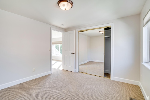 unfurnished bedroom with baseboards, carpet flooring, visible vents, and a closet