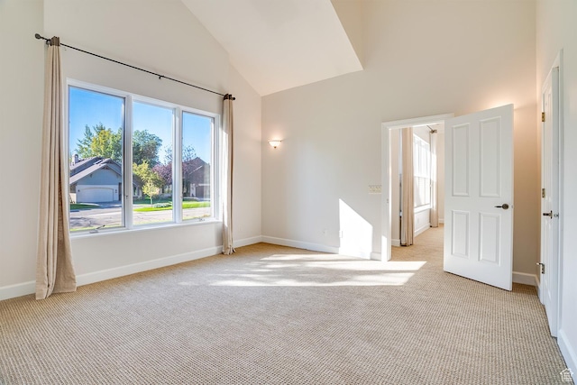 spare room with light carpet, baseboards, and high vaulted ceiling