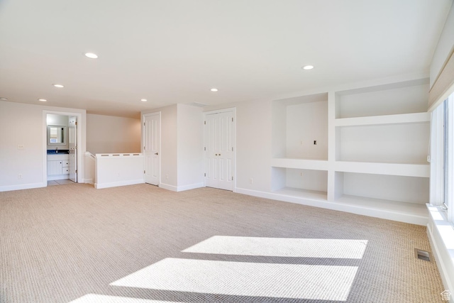 interior space featuring light carpet, baseboards, visible vents, recessed lighting, and built in features