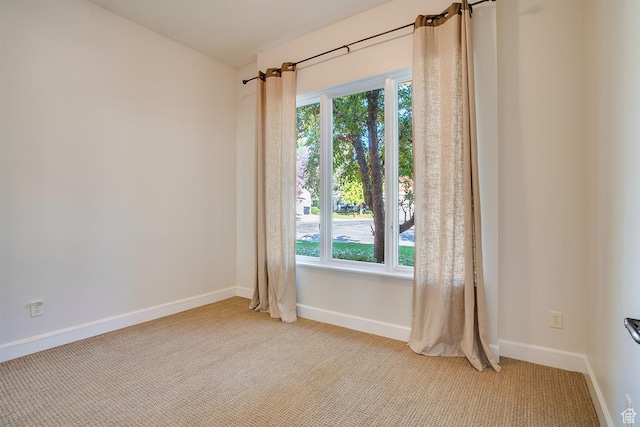 unfurnished room featuring plenty of natural light, baseboards, and light colored carpet