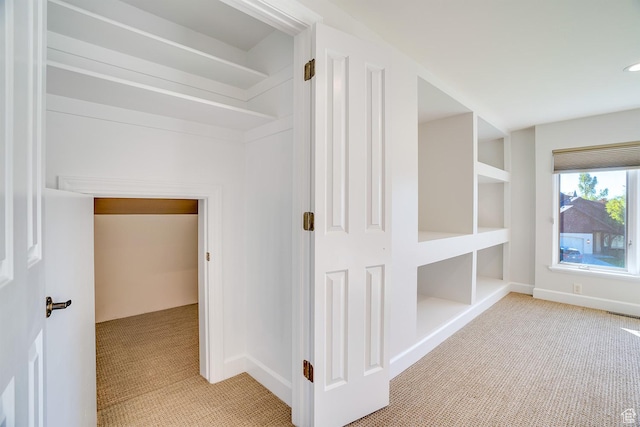 hall featuring baseboards and light colored carpet