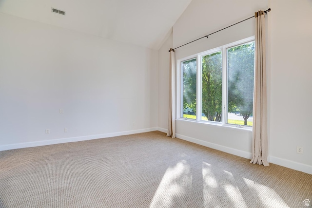 empty room featuring visible vents, light carpet, vaulted ceiling, and baseboards