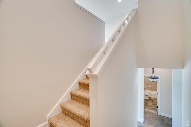 stairs featuring baseboards and stone finish floor