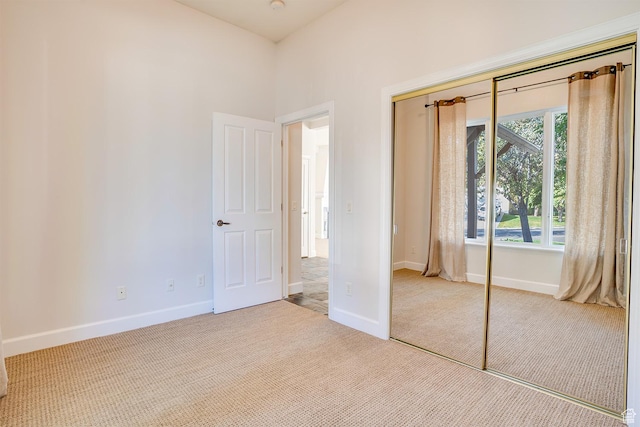 unfurnished bedroom with baseboards, carpet flooring, and a closet