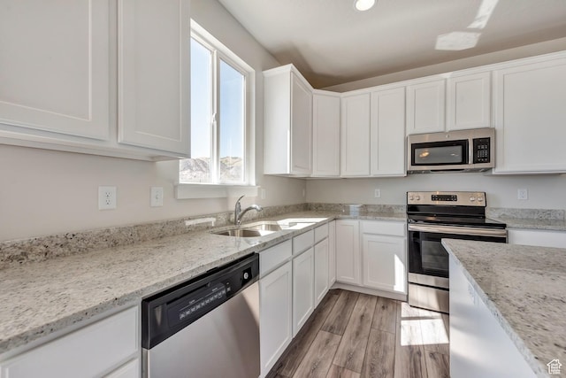 1777 S 3725th St W Unit 107, Taylor, UT 84401 - kitchen featuring stainless steel appliances, a sink, white cabinetry, light wood-style floors, and light stone countertops