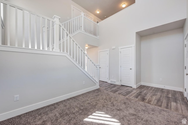 1777 S 3725th St W Unit 107, Taylor, UT 84401 - unfurnished living room featuring a towering ceiling, baseboards, stairs, and wood finished floors