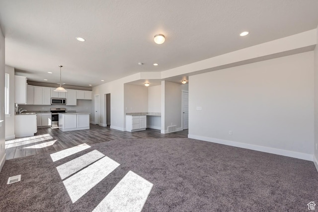 1777 S 3725th St W Unit 107, Taylor, UT 84401 - unfurnished living room featuring baseboards, recessed lighting, dark colored carpet, and dark wood finished floors