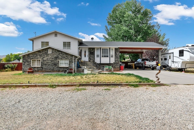 tri-level home featuring an attached carport, a front yard, brick siding, and driveway