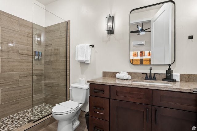 full bathroom featuring a tile shower, toilet, and vanity